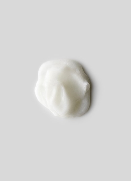 A small dollop of white cream or lotion on a light grey background.