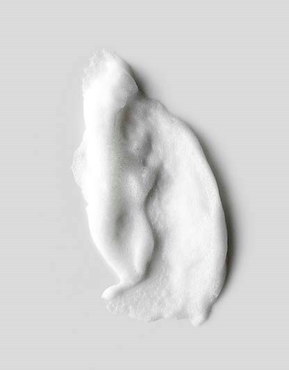 En fluffy vit molnliknande form på en grå bakgrund. Den har oregelbundna kanter och ett mjukt, bomullsliknande utseende.