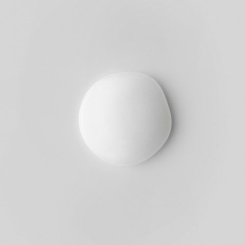 A white, round object on a light gray background, possibly a pill or a small ball.