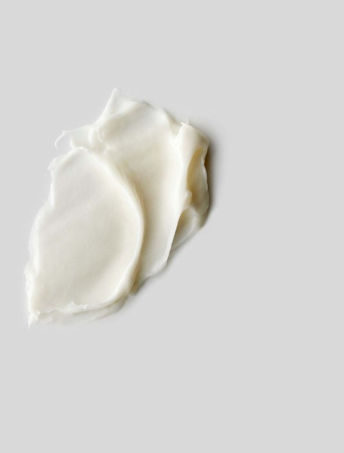 Några vita, krämiga bitar på en grå bakgrund, möjligtvis mat som ost eller lotion.