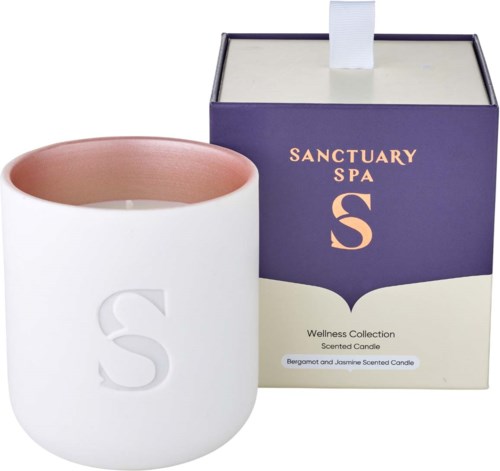 En vit ljushållare med ett stort 'S' och en lila och vit box märkt Sanctuary Spa S doftande ljus.