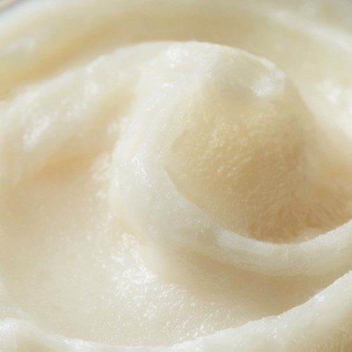 Close-up of a swirl of white, creamy substance, possibly butter or cream. Smooth and soft texture. No other elements present.
