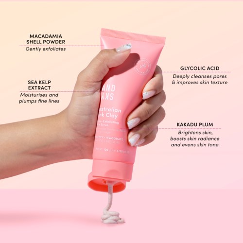 En hånd holder et rosa hudpleietube merket 'Australian Pink Clay'. Den har ingredienser som Macadamia skallpulver, tangekstrakt, glykolsyre og Kakadu-plomme.
