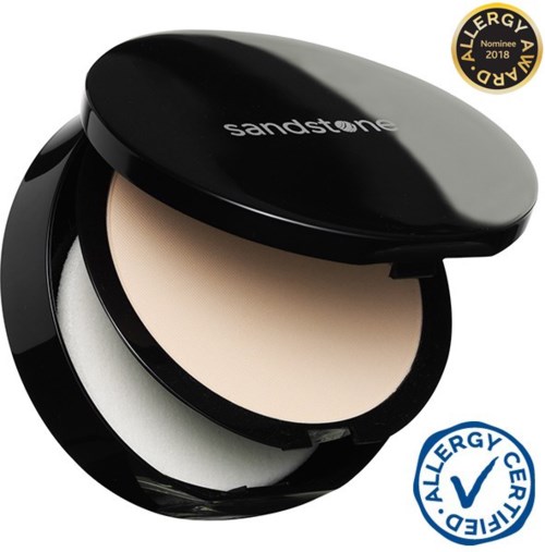En kompakt sminkask med beige puder, svart lock märkt 'sandstone' och allergimärkning.