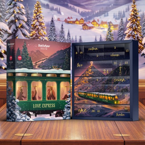 En juleinspirert adventskalender med tog og snølandskap, plassert på et trebord med snødekte trær i bakgrunnen.
