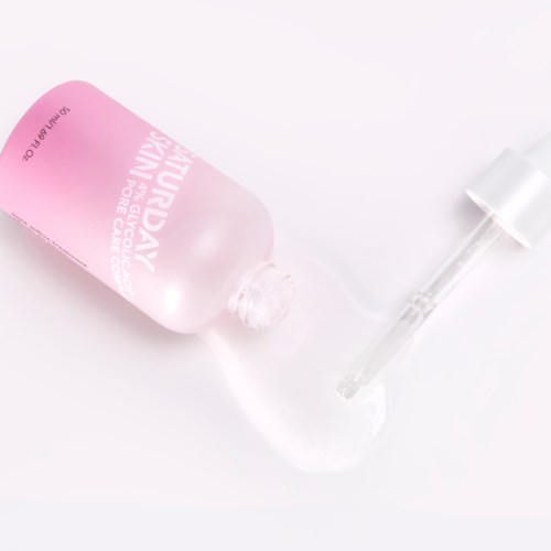 Eine pinke Flasche mit Tropfer liegt auf einer weißen Oberfläche.