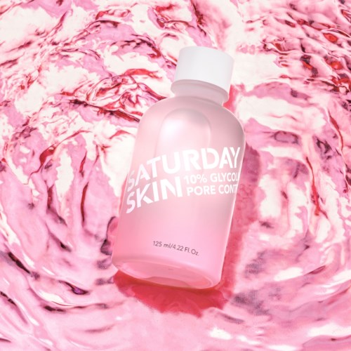 Rosa hudvårdsflaska med texten 'SATURDAY SKIN' och 10% glycolic pore control, ligger i rosa vatten.