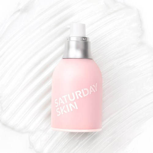 En ljus rosa hudvårdsflaska med vit och silver pump på en vit texturerad bakgrund.