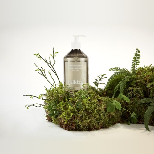 Een doorzichtige zeeppomp omringd door groene planten en mos, creëert een natuurlijke, milieuvriendelijke uitstraling.