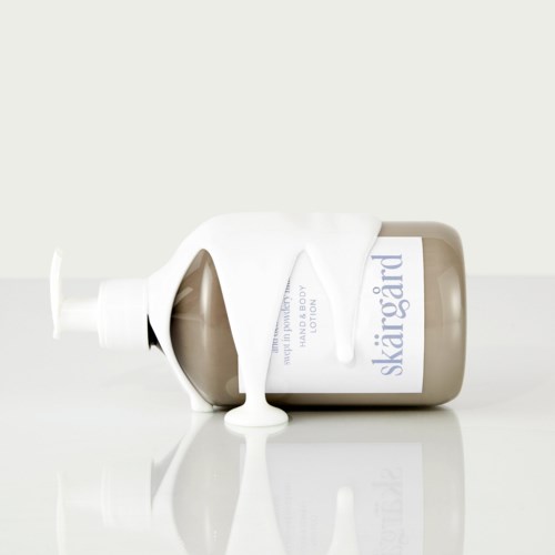 Eine Flasche Skargård Körperlotion mit ausgelaufener weißer Lotion. Die Flasche liegt auf einer weißen Oberfläche, größtenteils auf der Seite.