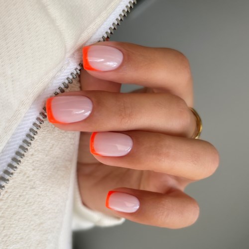 Hand with nails painted in a beige color and bright orange tips, holding a zipper. Simple and colorful design.