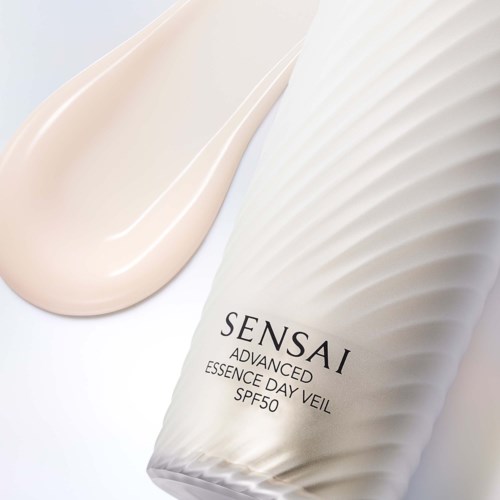 Een witte tube van Sensai Advanced Essence Day Veil met SPF50 en naast een gladde crème.
