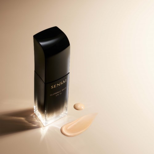Sort hudpleje flaske med lyserød creme og lidt creme under sollys.