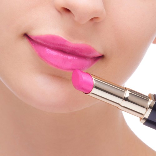 Eine Person trägt pinken Lippenstift auf die Lippen auf, Nahaufnahme des Gesichts, Fokus auf die Lippen.