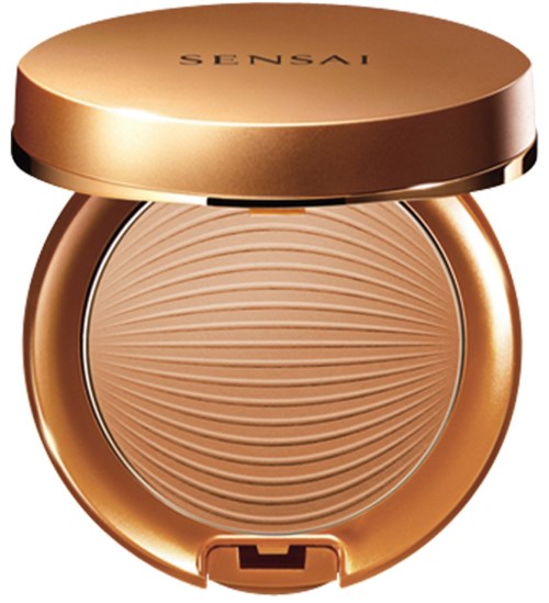 En liten dosa med guldkant och ett texturerat beige puder inuti.