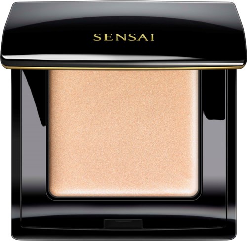 A black, shiny compact with gold lettering reading 'SENSAI' and a beige powder inside.