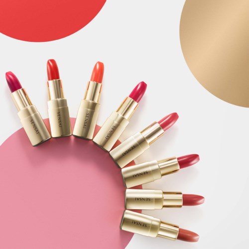 Zehn Lippenstifte in einem Kreis mit dekorativen bunten Kreisen um sie herum.