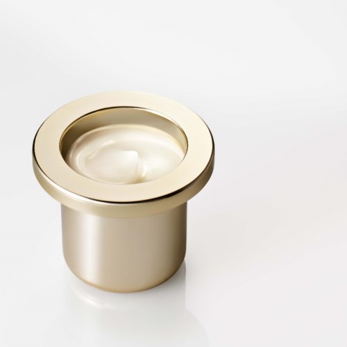 En liten rund behållare med glänsande metallkant och vitaktiga innehåll inuti.