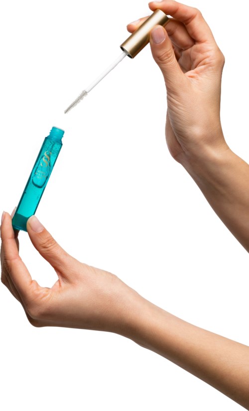 En person håller en liten flaska och droppar vätska med en pipett mot en vit bakgrund.