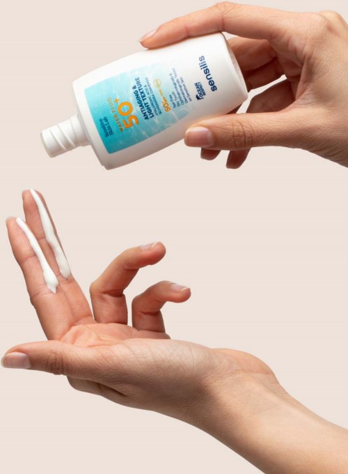 A person applying sunscreen lotion to their hand with a bottle labeled SPF 50.