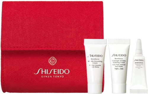 Een rood doosje met drie kleine witte huidverzorgingsproducten van Shiseido en een kleine druppelfles.