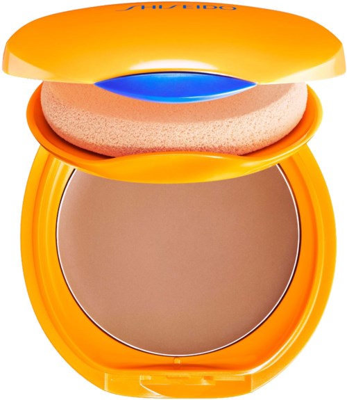 En compact med spejl, pudder og gul emballage, sandsynligvis til makeup.