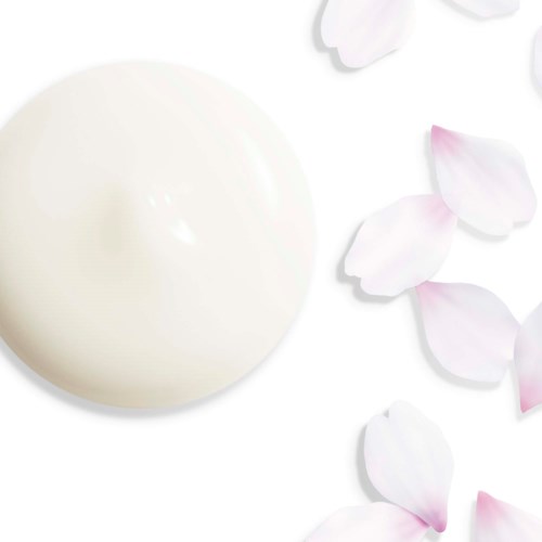 En krämig vit hudvårdsprodukt med spridda rosa och vita blomblad på vit bakgrund.