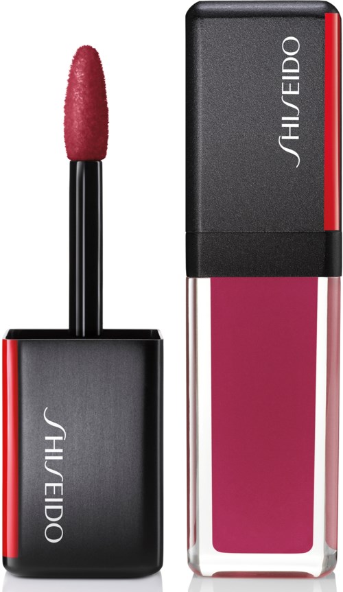 Läv pution lipgloss säiliö, jossa on vaaleanpunainen sävy, musta korkki ja Shiseido-merkki. Sen vieressä on suorakulmainen huulipunapakkaus.