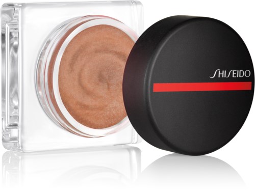 En beholder med Shiseido sminke, svart lokk og en ferskenfarget produkt inni.