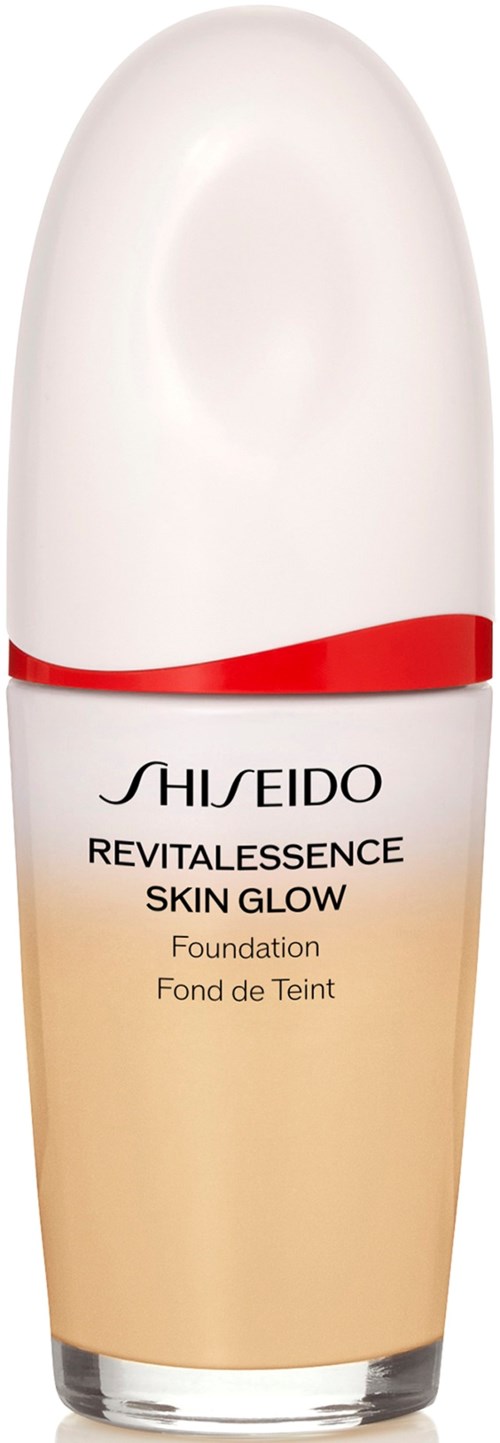 En foundationflaske med hvit hette og beige kropp, merket Shiseido Revitalessence Skin Glow.