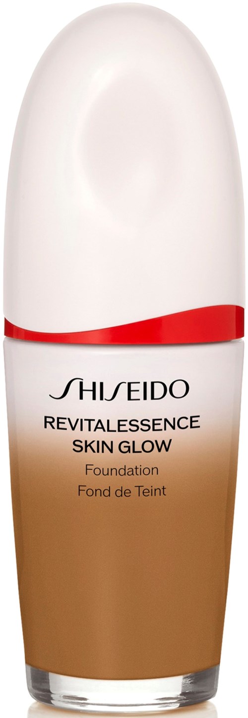 En flaske av Shiseido Revitalessence Skin Glow foundation med hvit lokk og rød design, som går fra hvitt til brunt.