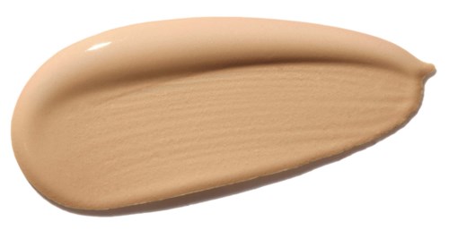 En beige væske eller krem spredt på en hvit bakgrunn, jevn og tykk i teksturen.