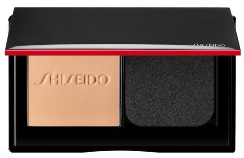 En liten makeup-ask med puder och en svamp inuti ett svart fodral, märkt Shiseido.