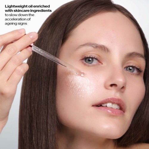 A woman applies skincare serum to her cheek using a dropper, promoting aging prevention with lightweight oil and skincare ingredients.