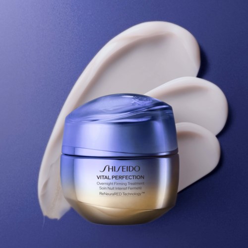 En krukke med Shiseido VITAL PERFECTION natcreme med cremepletter bagved på lilla baggrund.