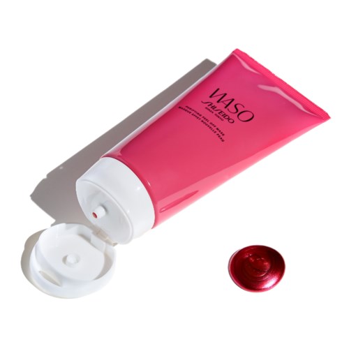A pink tube of skincare cream with an open cap and a red gel-like dollop beside it.