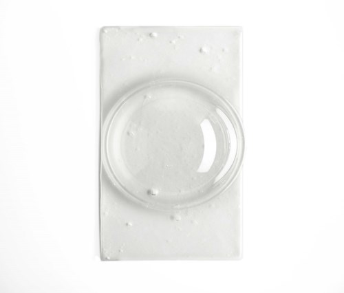 En klar rund linse på en hvid rektangulær base, minimalistisk og enkel i design.