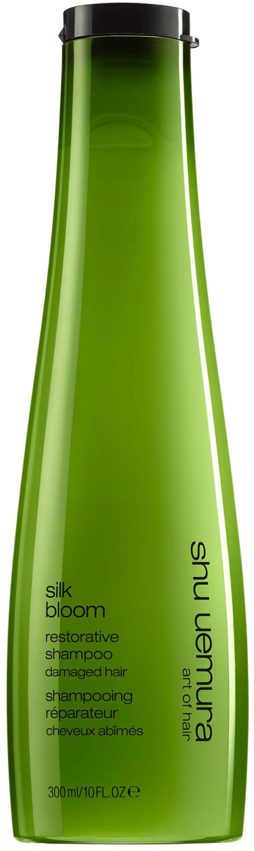 En lång, grön schampoflaska med svart lock, märkt Silk Bloom återställande schampo för skadat hår.