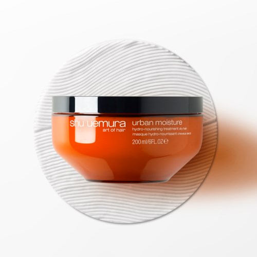En burk med Shu Uemura Urban Moisture vårdande hårinpackning på en vit texturerad bakgrund.