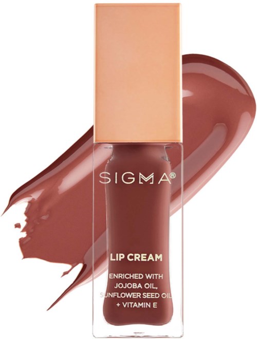 A brown lip cream bottle with a beige cap, surrounded by a smear of similar-colored product. The label shows "SIGMA" and details.