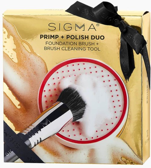 Låda med Sigma sminkborstar, inklusive foundationborste, rengöringsverktyg, gul förpackning, svart band och skumapplikator.