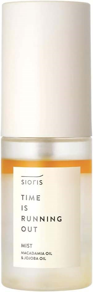 En hvit flaske med en etikett som sier "Time is Running Out Mist" med macadamia og jojobaolje.