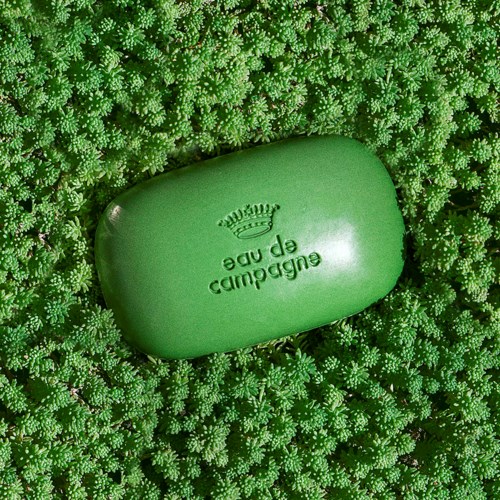 En grøn soap bar med et krone logo og teksten 'eudora de pe' på en bund af små grønne planter.