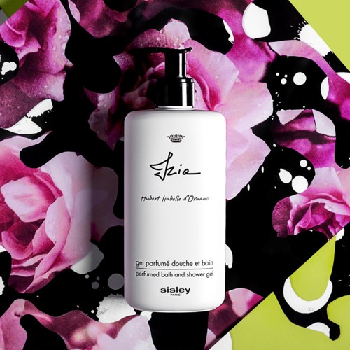 En vit flaska med pump, märkt 'Shia' parfymbad och duschgell, på en livfull rosa, svart och grönt abstrakt bakgrund.
