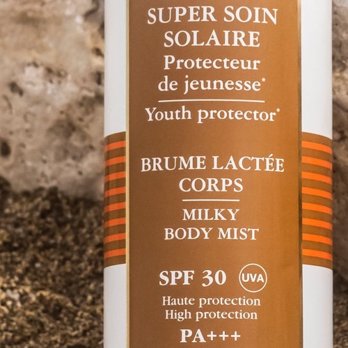 En flaska med solskyddsetikett: SPF 30, hög skydd, ungdoms- och kroppsmjölk, UVA-skydd, brunt och vitt design.