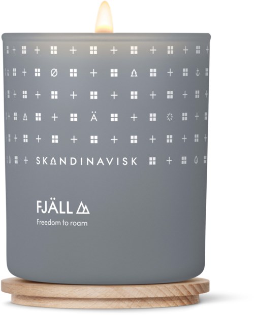 A grey candle with symbols and text, lit on a wooden base. It has Scandinavian brands and slogans.