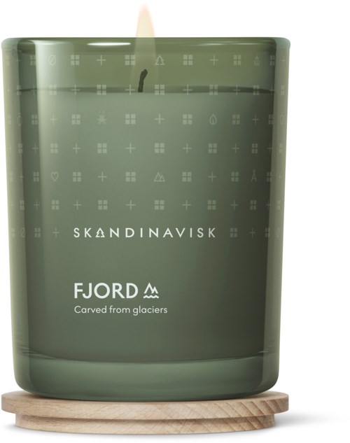 Een groene kaars met 'Skandinavisk' en 'Fjord' erop, op een houten ondergrond.