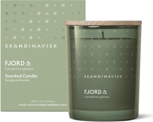 Een groene geurkaars in een glazen pot met houten deksel, en verpakking met Scandinavische symbolen en tekst.