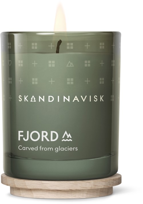Een groene kaars met de tekst 'FJORD' en 'Uitgemonsterd uit gletsjers' op een houten ondergrond.