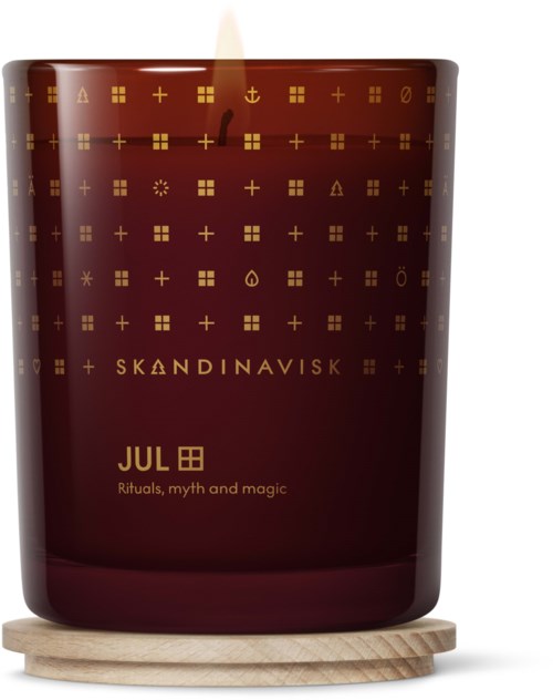 Et rødt lys med gullsymboler, kalt Skandinavisk, med tittelen "JUL," som symboliserer ritualer, myter og magi, plassert på en trebunn.
